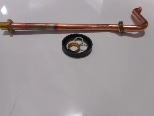 Kupfergasrohr mit einer gebogenen Endung und einem gewindeten Anschluss, daneben eine Dichtungssatz mit verschiedenen Ringen von der Marke Remeha.